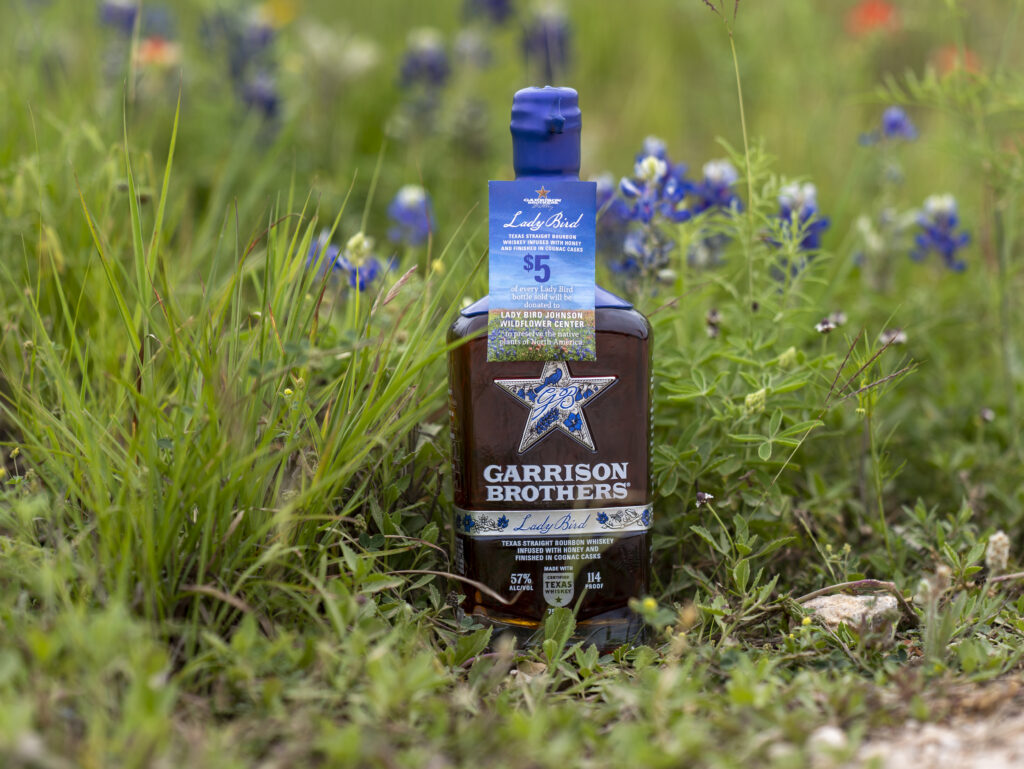 A bottle of Garrison Brothers Lady Bird Bourbon Whiskey with a seed packet neckhanger.