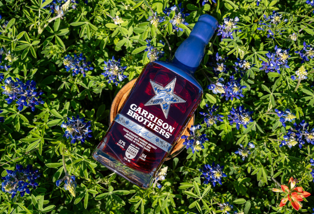 A bottle of Garrison Brothers Lady Bird Bourbon in blooming bluebonnets